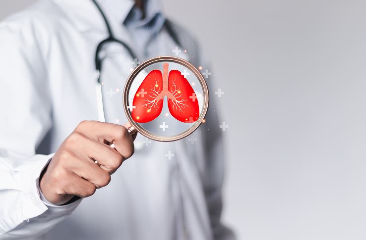 Un médecin en blouse blanche et stéthoscope tient une loupe devant une illustration de poumons rouges, symbolisant un examen médical des voies respiratoires