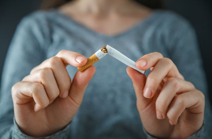 Une personne casse une cigarette en deux entre ses doigts, symbolisant l'arrêt du tabac